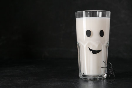Glass of milk and spider for Halloween on dark background, closeupの写真素材