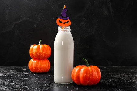 Bottle of milk and pumpkins for Halloween on dark backgroundの写真素材