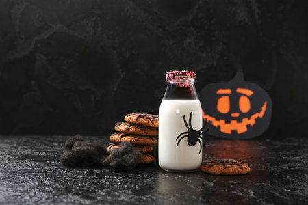 Bottle of milk, spider and tasty cookies for Halloween on dark backgroundの写真素材