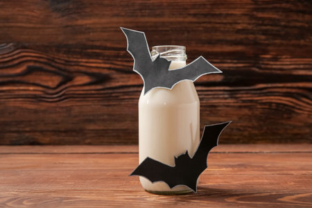 Bottle of milk and bats made of paper for Halloween on wooden background, closeupの写真素材