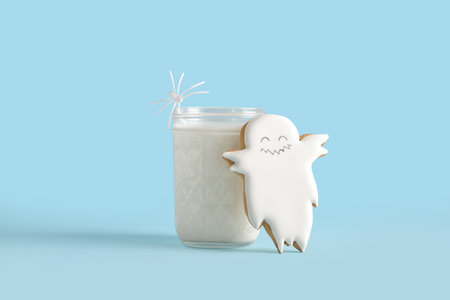 Glass of milk and tasty cookie for Halloween on blue backgroundの写真素材