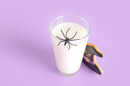 Glass of milk, spider and tasty cookie for Halloween on purple background, closeupの写真素材