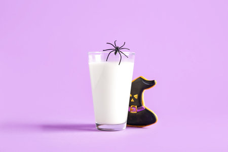 Glass of milk, spider and tasty cookie for Halloween on purple backgroundの写真素材