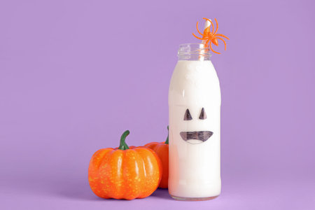 Bottle of milk and pumpkins for Halloween on purple backgroundの写真素材