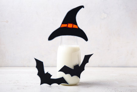 Bottle of milk, hat and bats made of paper for Halloween on light backgroundの写真素材