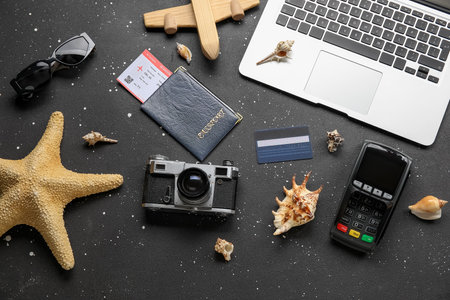 Composition with payment terminal, passport, laptop and photo camera on dark backgroundの写真素材