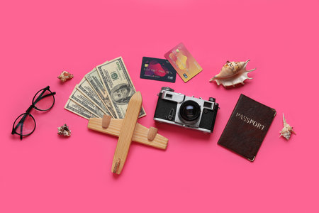 Composition with credit cards, money, wooden plane and photo camera on pink backgroundの写真素材