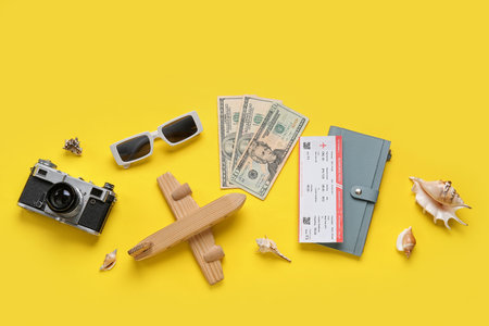 Composition with money, ticket, wooden plane and sunglasses on yellow backgroundの写真素材