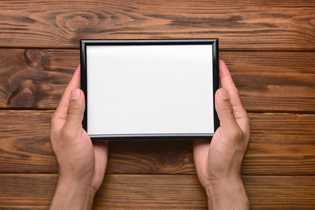 Man holding blank photo frame on wooden backgroundの写真素材