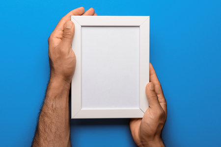 Man holding blank photo frame on blue backgroundの写真素材