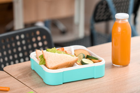 School lunchbox with bottle of juice on table in classroom, closeupの写真素材
