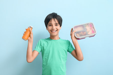 Little boy with lunchbox and bottle of juice on blue backgroundの写真素材