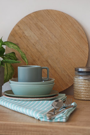 Clean dishes, houseplant, cutlery and jar on wooden counterの写真素材