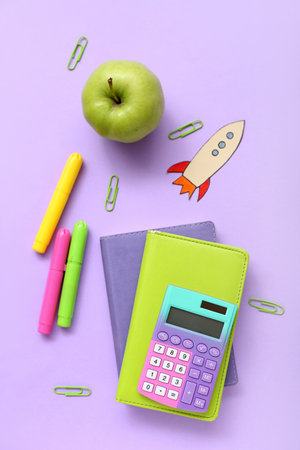 Paper rocket with school stationery and apple on purple backgroundの写真素材