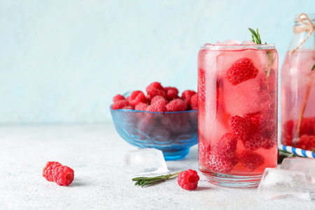 Glass and bottle of fresh raspberry lemonade with rosemary on white tableの写真素材
