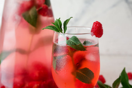 Bottle and glass of fresh raspberry lemonade with mint on white background