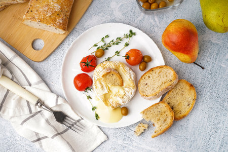 Plate of tasty baked Camembert cheese on light backgroundの写真素材