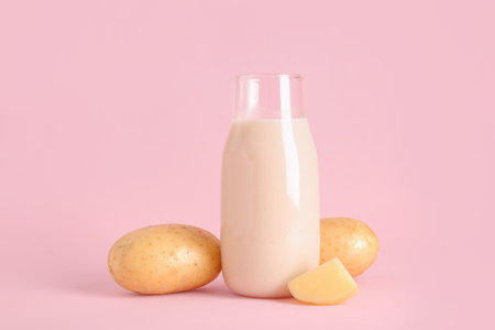 Bottle of tasty potato milk on pink backgroundの写真素材