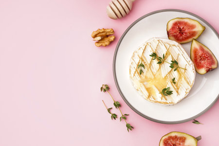 Plate of tasty baked Camembert cheese on pink backgroundの写真素材