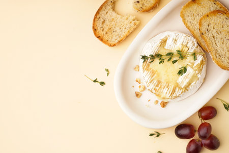 plate of tasty baked Camembert cheese with bread on yellow backgroundの写真素材
