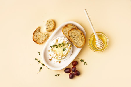 plate of tasty baked Camembert cheese with bread on yellow backgroundの写真素材