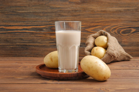 Glass of tasty potato milk on wooden backgroundの写真素材