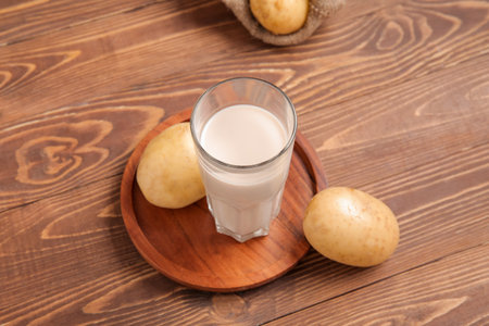 Glass of tasty potato milk on wooden backgroundの写真素材