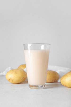 Glass of tasty potato milk on light backgroundの写真素材