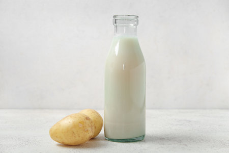 Bottle of tasty potato milk on light backgroundの写真素材