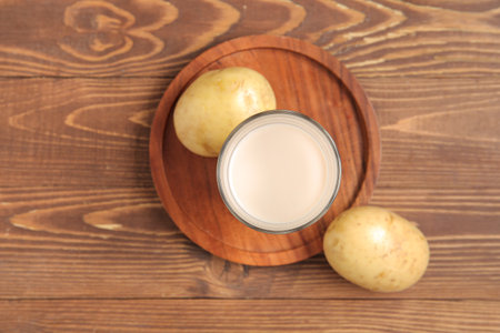 Glass of tasty potato milk on wooden backgroundの写真素材