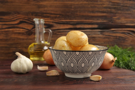 Bowl with raw potatoes on wooden backgroundの写真素材