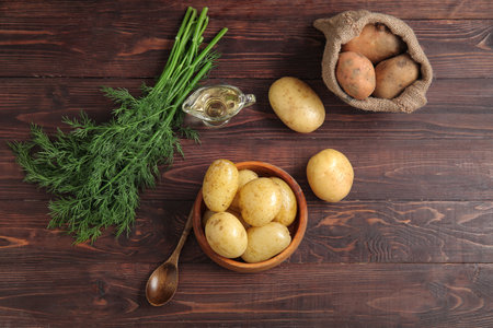Bowl with sack bag of raw potatoes on wooden backgroundの写真素材