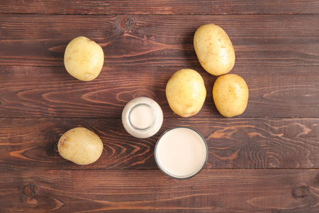 Bottle and glass of tasty potato milk on wooden backgroundの写真素材
