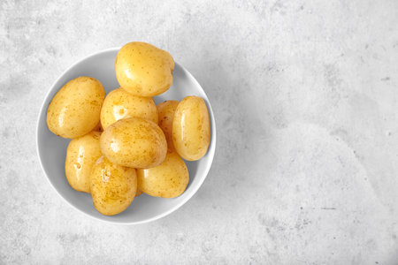 Bowl with raw potatoes on light backgroundの写真素材