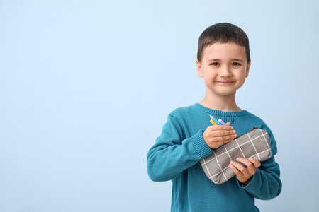 Cute little boy with pencil case on blue backgroundの写真素材