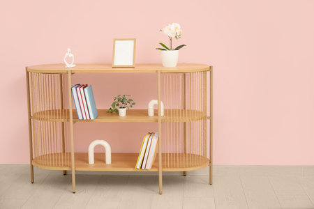 Bookshelf with flowers near pink wall in roomの写真素材