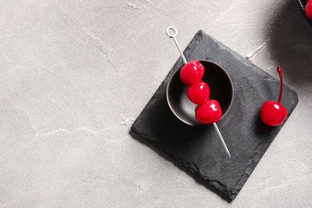 Bowl of tasty maraschino cherries on gray backgroundの写真素材