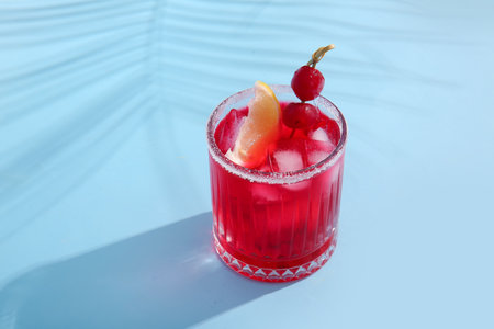 Glass of tasty cocktail with maraschino cherries on blue backgroundの写真素材