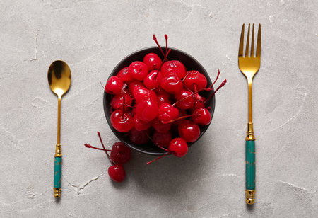 Bowl of tasty maraschino cherries on gray backgroundの写真素材