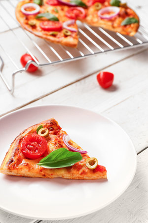Plate with tasty pizza, ingredients and grid on white wooden backgroundの写真素材