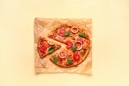 Tasty pizza with olives, tomatoes and basil on yellow backgroundの写真素材