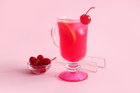 Bowl of tasty maraschino cherries and glass cup with cold cocktail on pink backgroundの写真素材