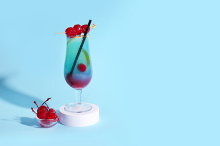 Bowl of tasty maraschino cherries and glass with cold cocktail on blue backgroundの写真素材