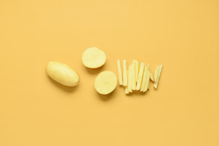 Whole and cut potatoes on yellow backgroundの写真素材