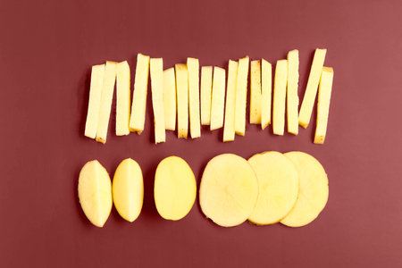 Pieces of raw potato on brown backgroundの写真素材