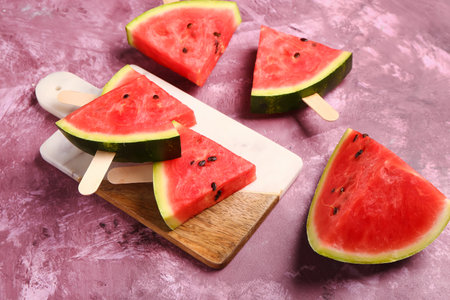 Board with sweet watermelon sticks on purple backgroundの写真素材