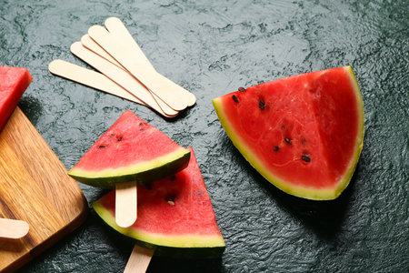 Wooden board with sweet watermelon sticks on green backgroundの写真素材