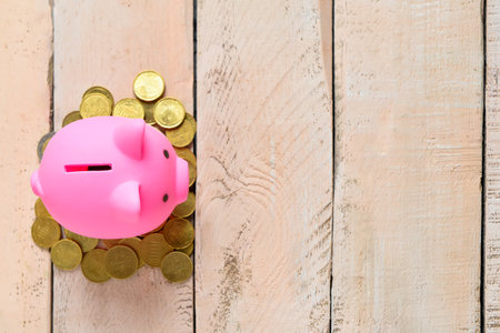 Pink piggy bank with coins on light wooden backgroundの写真素材