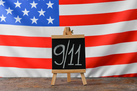 Blackboard with date of National Day of Prayer and Remembrance for the Victims of the Terrorist Attacks on table against USA flagの写真素材
