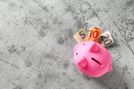 Piggy bank with euro banknotes on grunge gray backgroundの写真素材